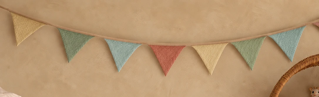 Guirnalda de banderines de muselina en tonos pastel, colgada en la pared
