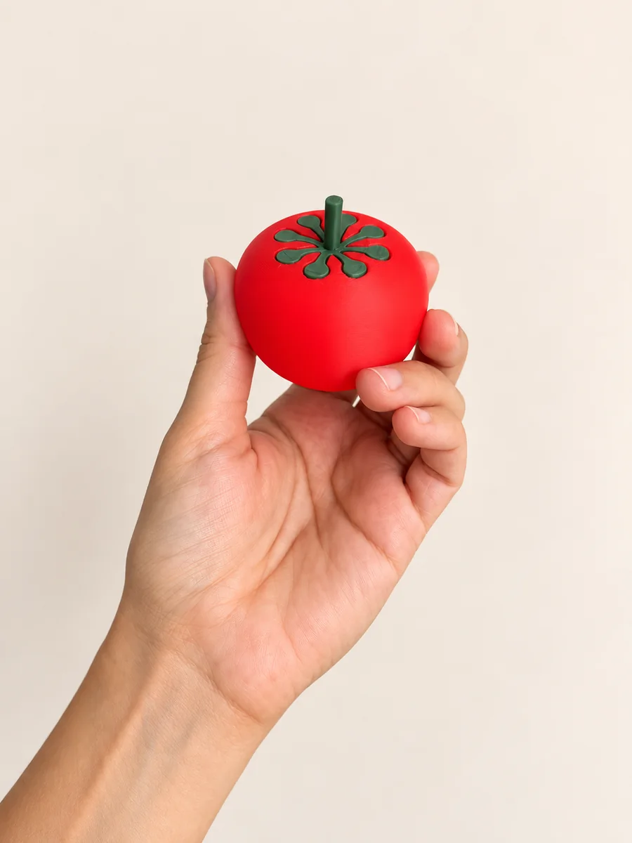 Tomate giratorio rojo con espiral y tallo verdes, sostenido en una mano